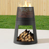 Black outdoor fire pit with burning wood and logs on a grassy background
