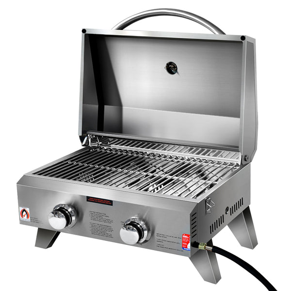 A portable stainless steel Grillz gas BBQ grill with two burners, open lid showing grates, set up on retractable legs with a carrying handle and on a white background.