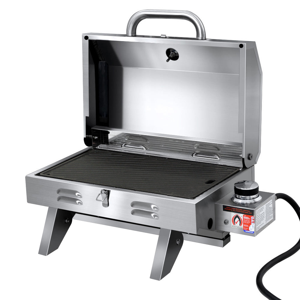 A portable stainless steel Grillz gas BBQ grill with a double-sided plate, retractable steel legs, and a large front carry handle, displayed in its opened configuration; on a white background.