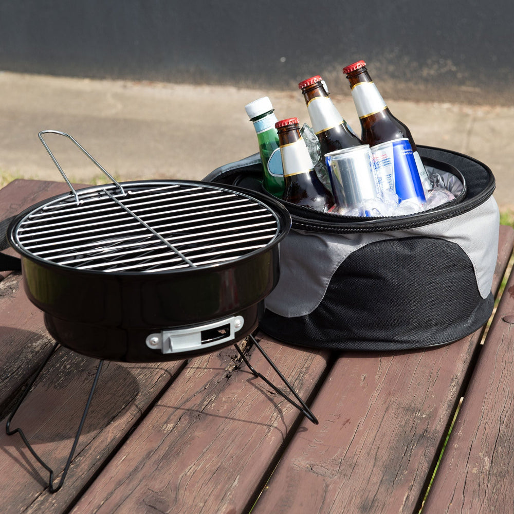 Portable grill with a cooler full of drinks on a wooden surface.