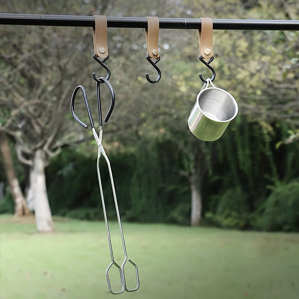 Metal tongs and cup hanging on a hook with a natural outdoor background