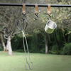 Metal tongs and cup hanging on a hook with a natural outdoor background