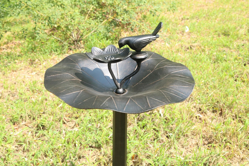 Decorative bird bath with a bird design on a grassy background
