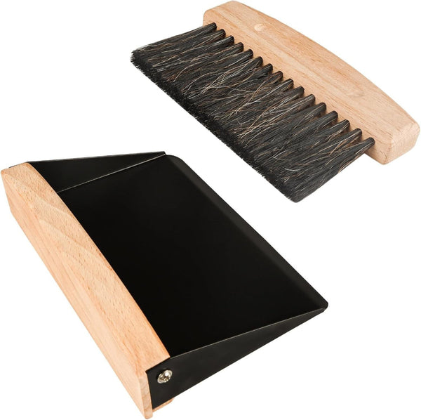 Wooden brush with black bristles and a black dustpan on a white background