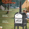 Black outdoor pizza oven with features highlighted, set against a grassy background with people and a tent.