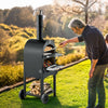 Man cooking pizza on a portable outdoor oven in a park setting