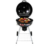 A portable charcoal BBQ smoker with an enameled firebowl and lid, in a tripod design. It has wheels and a storage shelf beneath, lid is open showing meat cooked on the grill top.