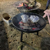 Barbecue grill with two pieces of meat on a dirt ground