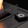 Planika stove with glass cover and flame, featuring the brand name.