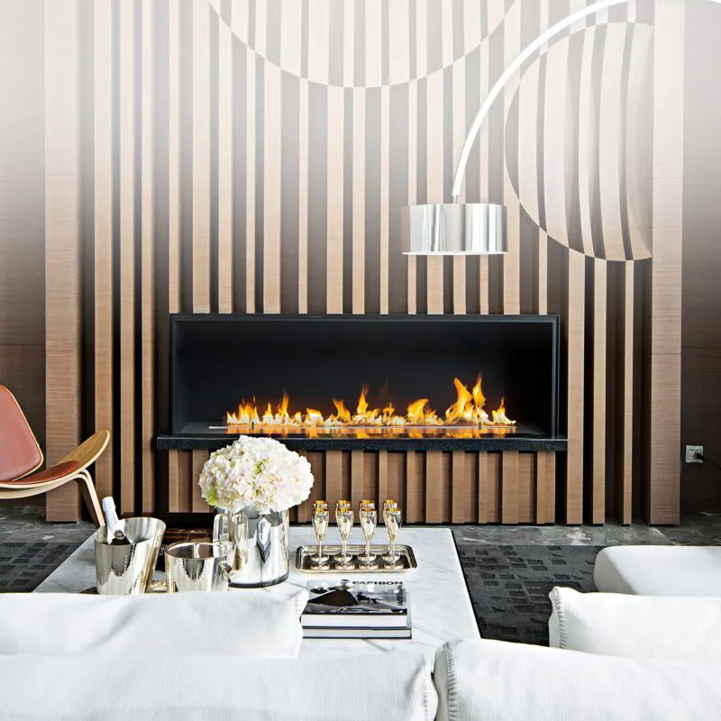 Modern living room with a fireplace, striped wall, and decorative items.