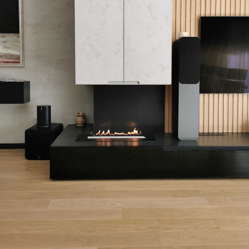 Modern living room with a black fireplace, speakers, and a television.