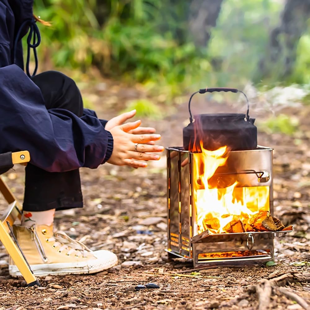 Person sitting by a campfire with a metal stove and kettle in a forest setting