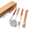 Set of four barbecue utensils with wooden handles on a white background