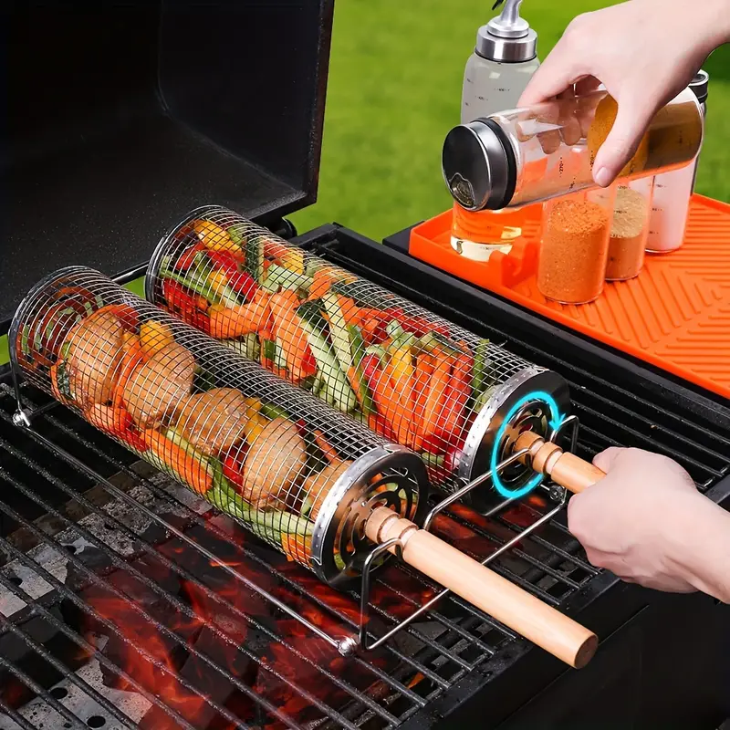 Person using a stainless-steel rotating grill basket with vegetables on a barbecue