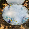 Cauldron round stainless-steel fire pit being used to chill drinks, filled with lots of ice and small glass bottles.