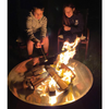 Two children sitting beside a round shaped polished mirror finished stainless steel fire pit and toasting marshmellows.