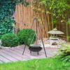 A black tripod garden fire pit with a round bowl on top, with a heat-resistant coating and a metal grill, set in a Japanese style garden.