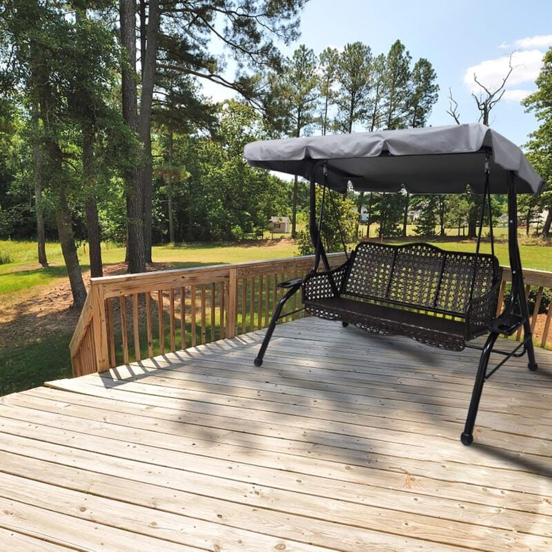 Wicker swing with canopy on a wooden deck surrounded by trees