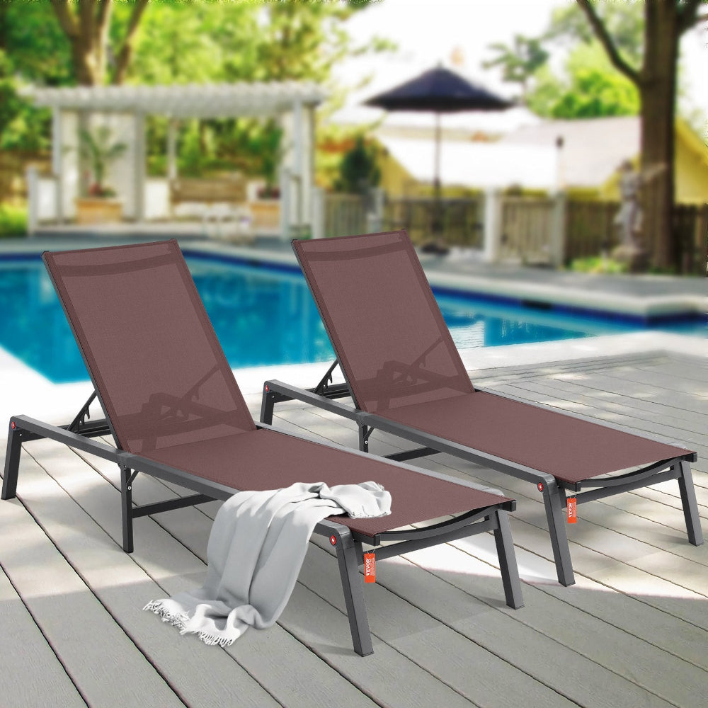Two brown lounge chairs on a wooden deck by a pool with a blurred background