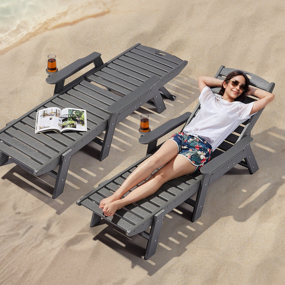Person relaxing on a beach chair with a magazine and drink, on a sandy background