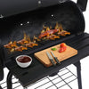 Barbecue grill with food being cooked, a cutting board with vegetables, and a bowl of sauce.