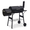 A free-standing black offset smoker grill with a side firebox, cooking grids, and a set of wheels for mobility. It has a chimney on one side and a lid thermometer on top.