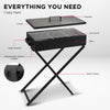A portable charcoal grill with lid and foldable legs on a stand on a white background showcasing all the individual parts.