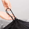 Person holding a black drawstring on a black bag against a gray background