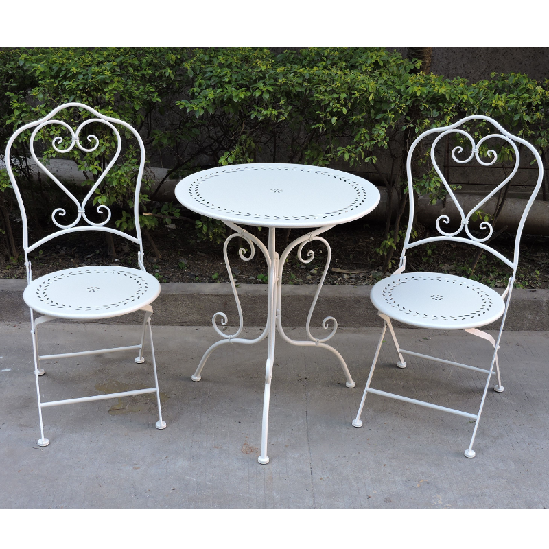 Zoe Wrought Iron Bistro 3 Piece Setting in white colour set up on a cement floor area with garden hedging in the backdrop.