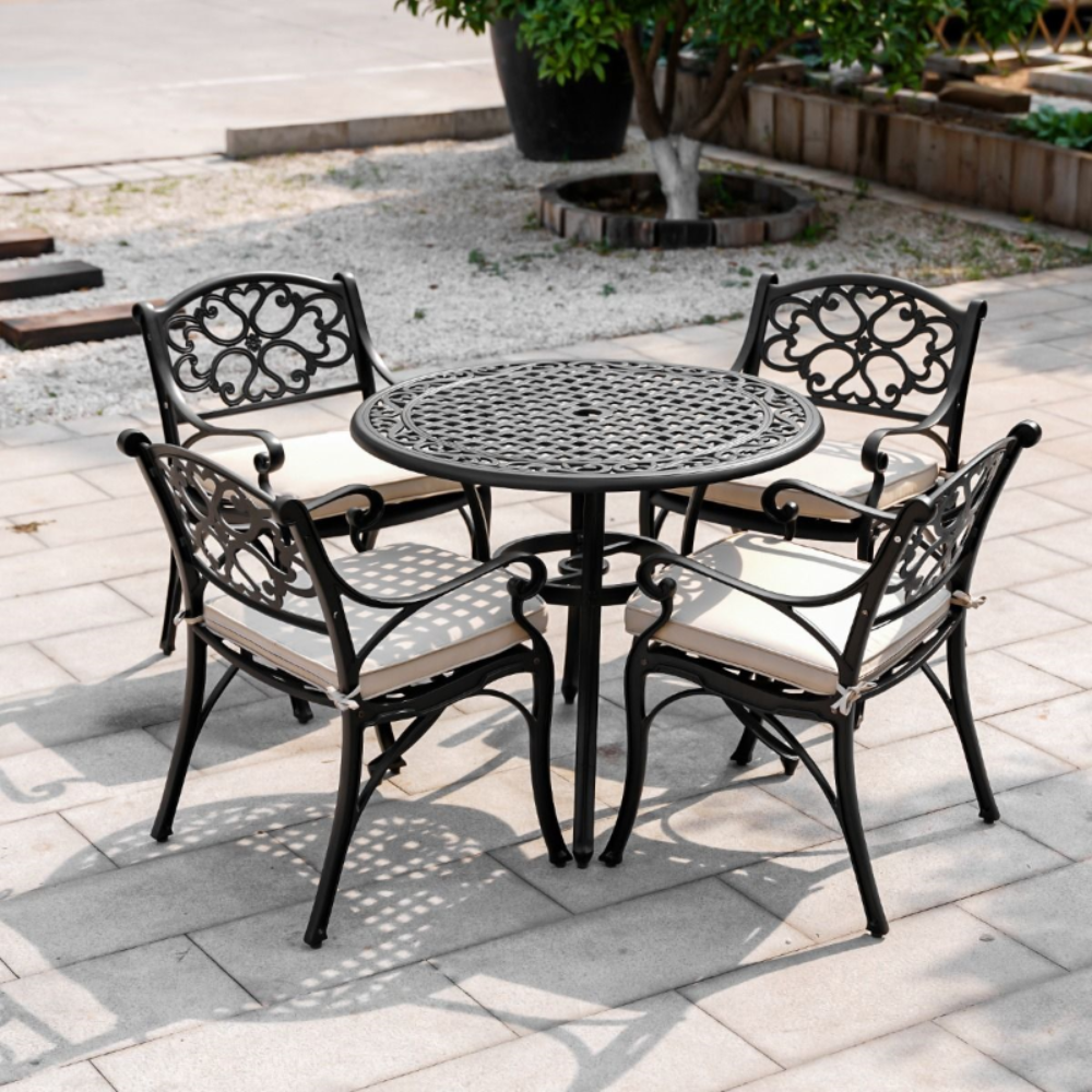 Marco 5 piece Black Outdoor Setting in a garden on cement tiled area with small stone ground cover close by and a tree in the background.
