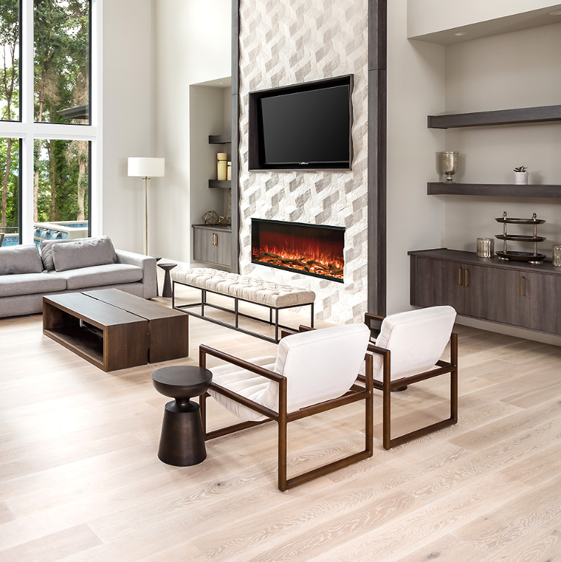 Astro 1200 Electric Fireplace Single sided Installed in a lounge room wall with a TV hanging above it, wall shelves and cupboards both sides with various ornaments on, a lounge suite, a padded bench seat, two chairs, coffee tables and few side tables, a lampshade in the corner of room. End of a swimming pool and tall trees can be seen through the window.