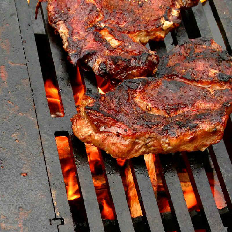 Close up view of BBQ steaks cooking on a Yagoona Barramundi BBQ Grill.