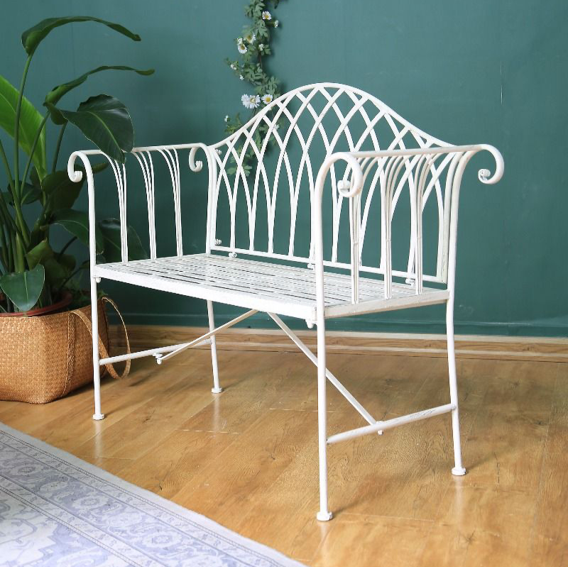 Antique White coloured Lavinia Iron Bench Australia indoors in a room with turquoise painted wall, floorboards, hanging daisy's and a plant in cane basket next to the bench seat.