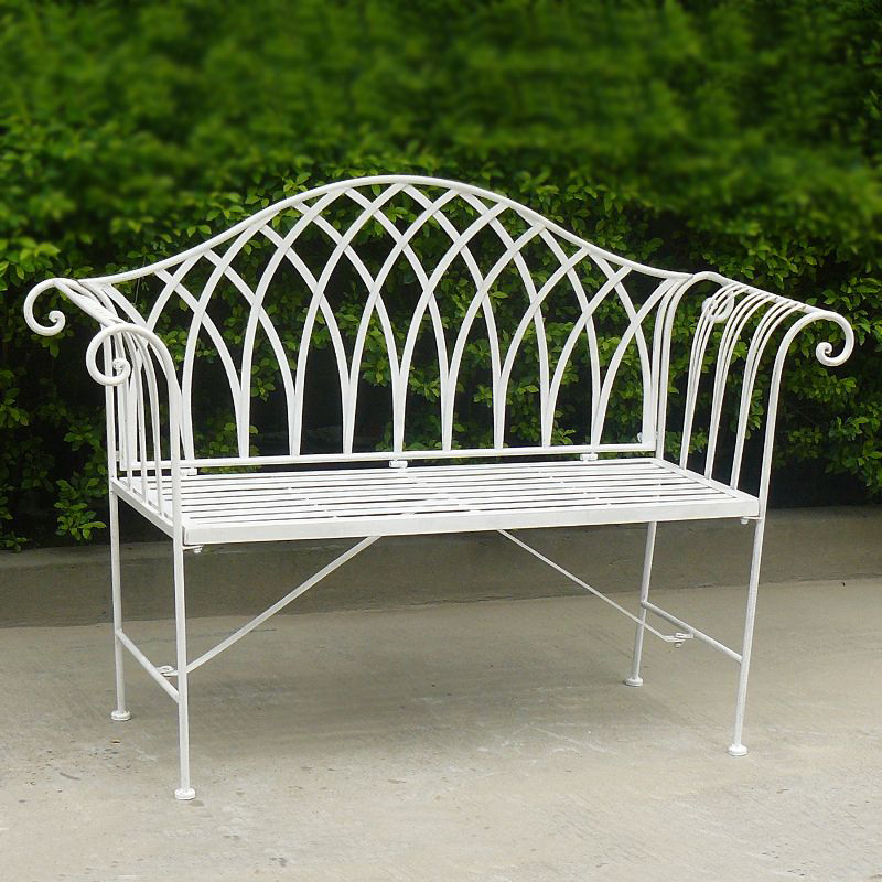 Lavinia Antique white colour Iron Bench in front of some bushes on a cemented area.