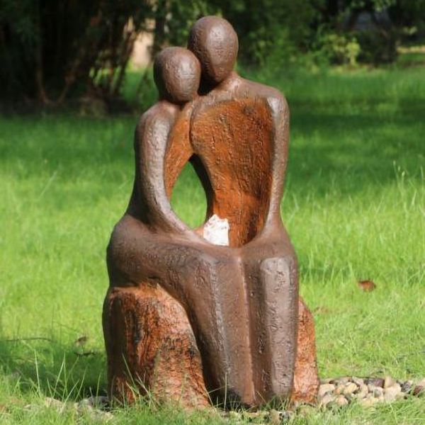 Lovers Water Fountain with bubbling water and with grass, trees and small pebbles surrounding.