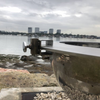 Teppanyaki Spit Rotisserie Bracket on side of the fire pit beside a body of water, buildings and boats in the background