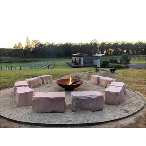 The Cauldron Fire Pit 1500mm in rural setting with large stone seats around it