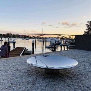 The Cauldron 100cm Stainless Steel Fire Pit and poker at a seaside setting
