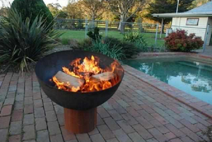 The Goblet Fire Pit with fire burning beside a pool