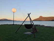 Load image into Gallery viewer, The Tripod Fire Pit on lawn at a lake side