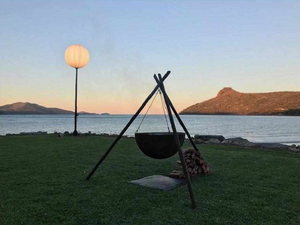 The Tripod Fire Pit on lawn at a lake side