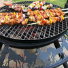 The Ultimate BBQ Fire Pit in the stockman design, grilling kebab sticks with chicken and vegetable chunks.