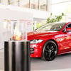 Totem Commerce Ethanol Burner in a commercial car showroom in Poland, set beside a red car and office behind them.